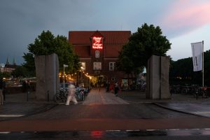 Außenansicht der Weserburg in der Dämmerung, davor läuft eine Person