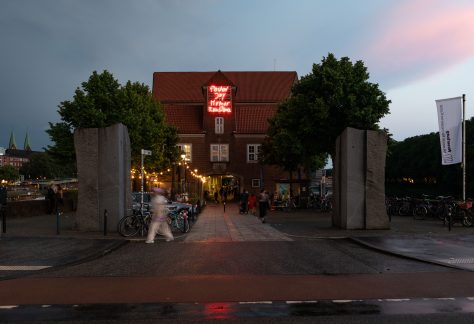 Außenansicht der Weserburg in der Dämmerung, davor läuft eine Person