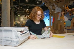 Junges Mädchen faltet einen Papierflieger aus Zeitungspapier