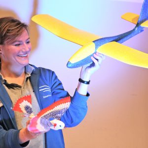 Junge Frau mit Vogel und Flugzeug in der Hand