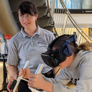 Mitarbeiterin vom Universum Bremen betreut einen Gast an einem Exponat