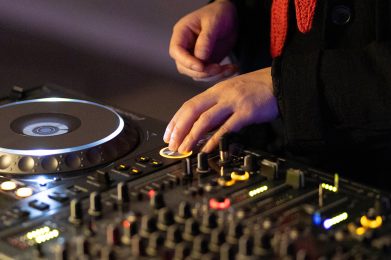 Zwei Hände, die an DJ-Turntables liegen