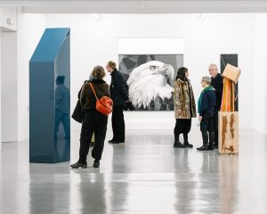 Mehrere Menschen, die vor unterschiedlichen künstlerischen Stählen in einer Ausstellung stehen.