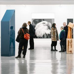 Mehrere Menschen, die vor unterschiedlichen künstlerischen Stählen in einer Ausstellung stehen.