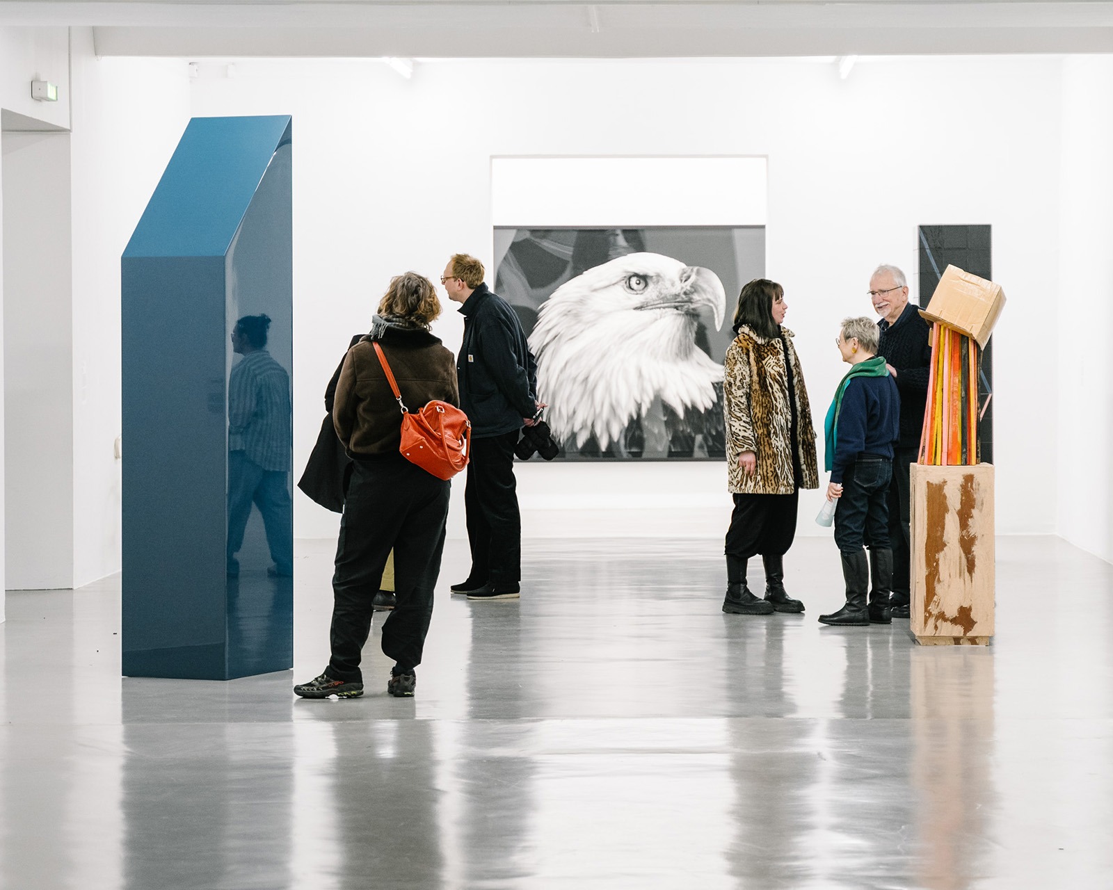 Mehrere Menschen, die vor unterschiedlichen künstlerischen Stählen in einer Ausstellung stehen.