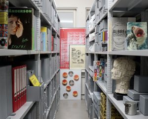 Archivregalreihen mit Büchern, Skulpturen, Schallplatten und Ordnern