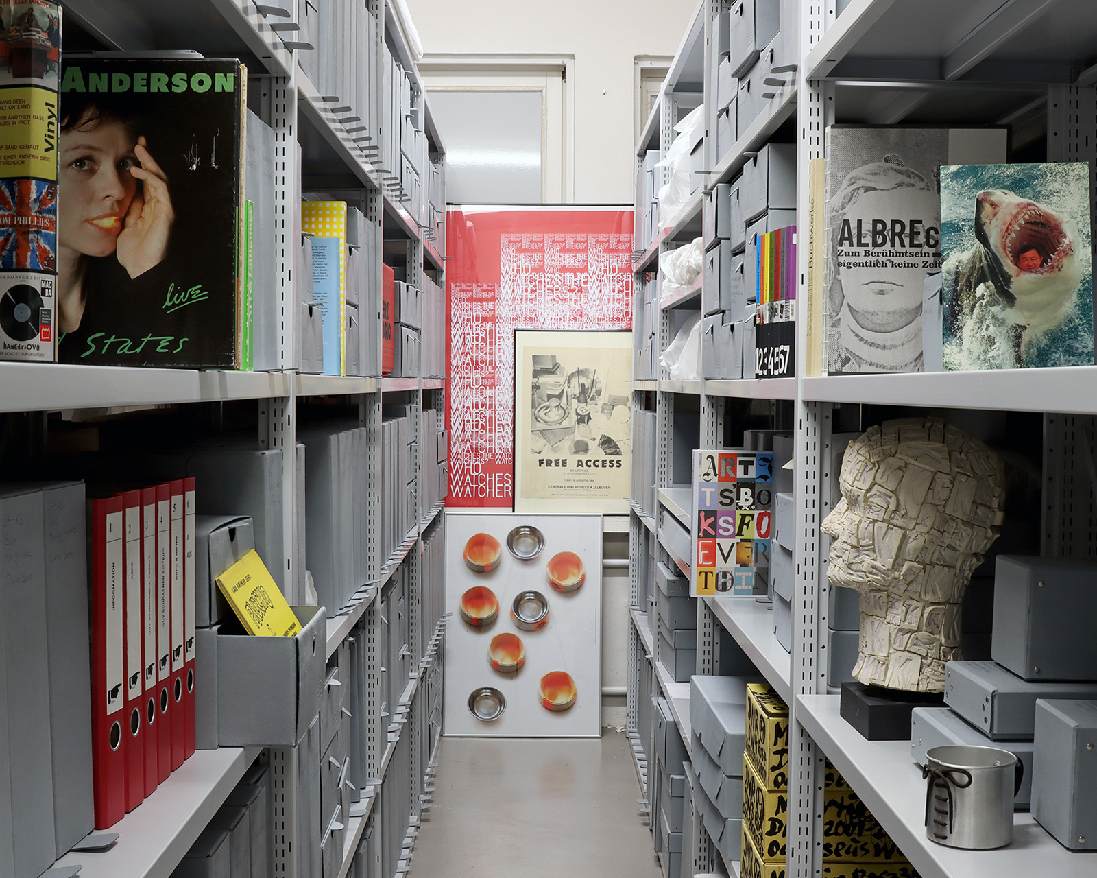 Archivregalreihen mit Büchern, Skulpturen, Schallplatten und Ordnern
